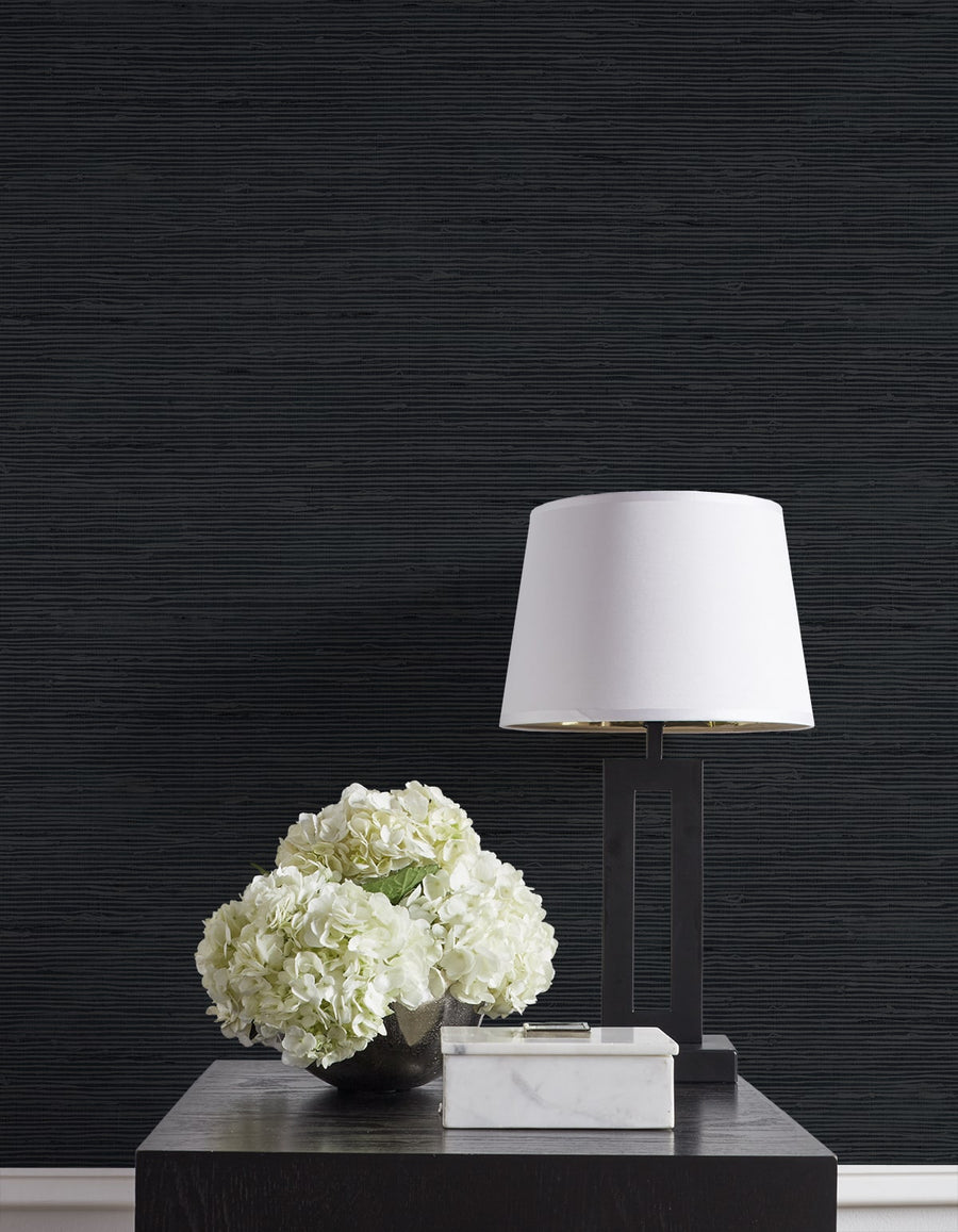 White lamp and floral arrangement on a dark textured wall