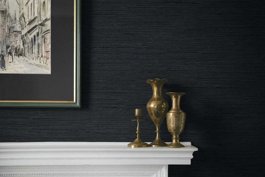 Decorative mantelpiece with gold vases and a candlestick against a dark textured wall.
