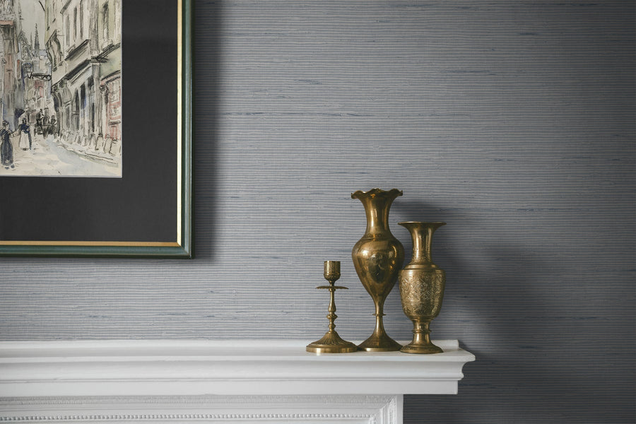 Decorative mantelpiece with gold vases and a candlestick against a textured gray wall.