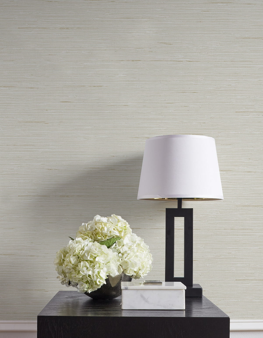 Modern lamp and floral arrangement on a table against a textured wall.