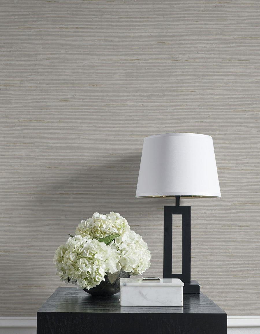 White lamp and floral arrangement on a dark surface with a neutral wall background