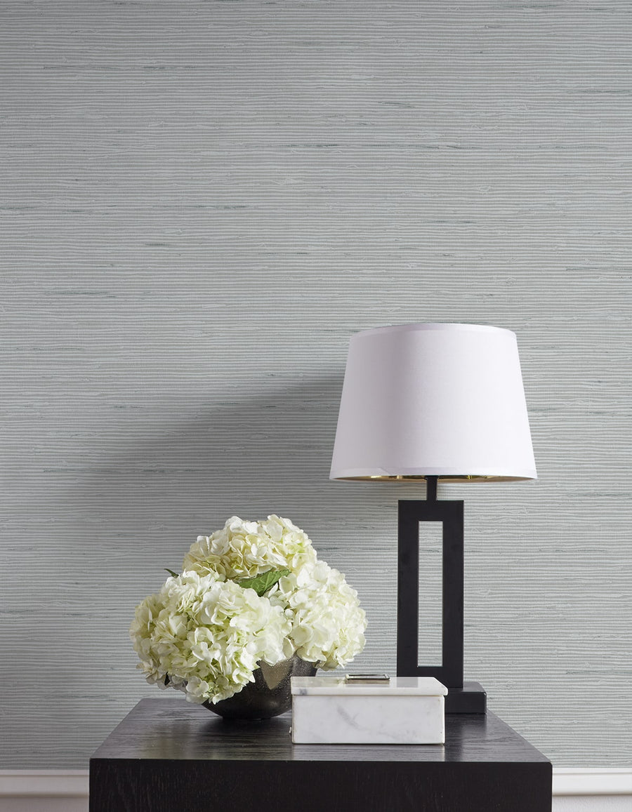 Table with a lamp and flowers against a textured gray wall