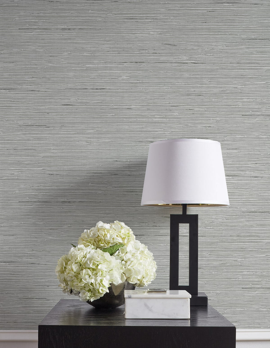 Table with a lamp and floral arrangement against a textured gray wall