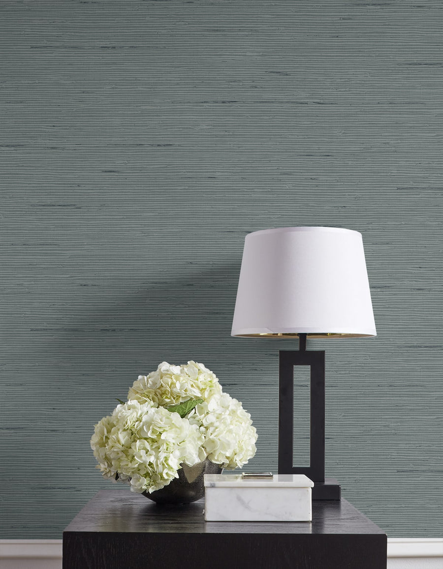 Decorative table with a lamp and flowers against a textured gray wall.