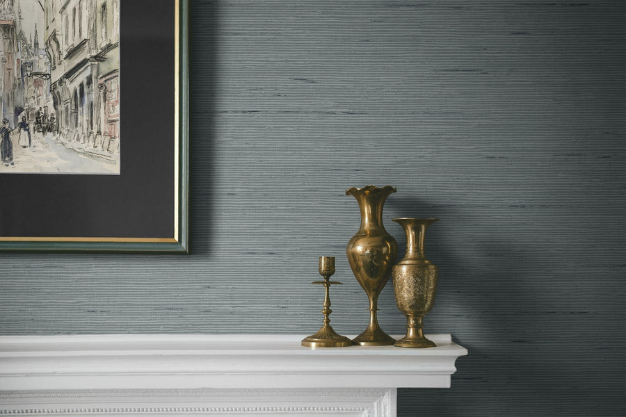 Decorative mantelpiece with gold vases and a candlestick against a textured gray wall.