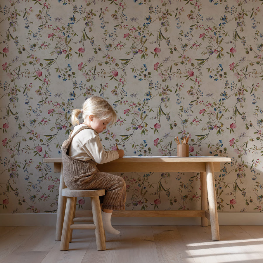 Child sitting at a wooden table with a Watercolor Wildflower Wallpaper – Pink, Blue & Green Floral