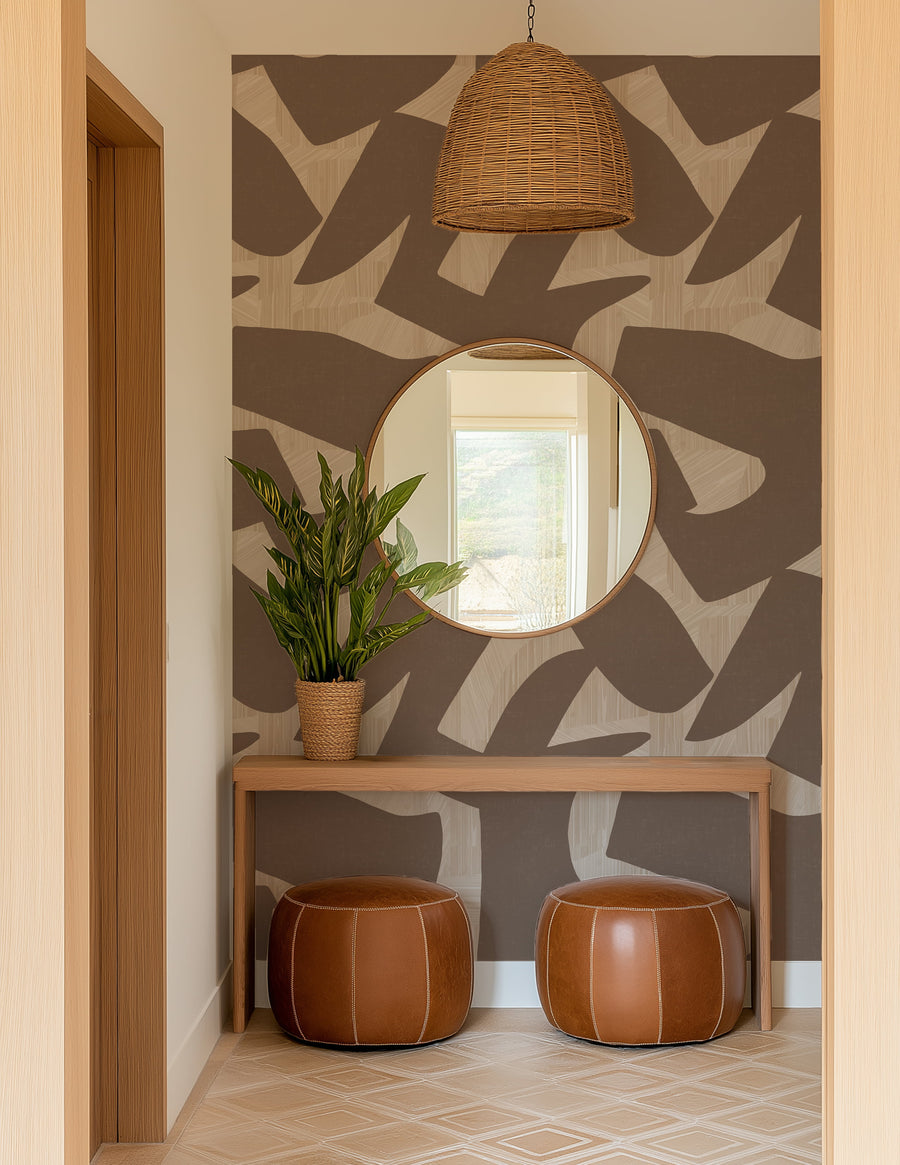 Modern interior with a round mirror, plant, and brown ottomans against an Abstract Intarsia Wallpaper – Brown & Cream Texture