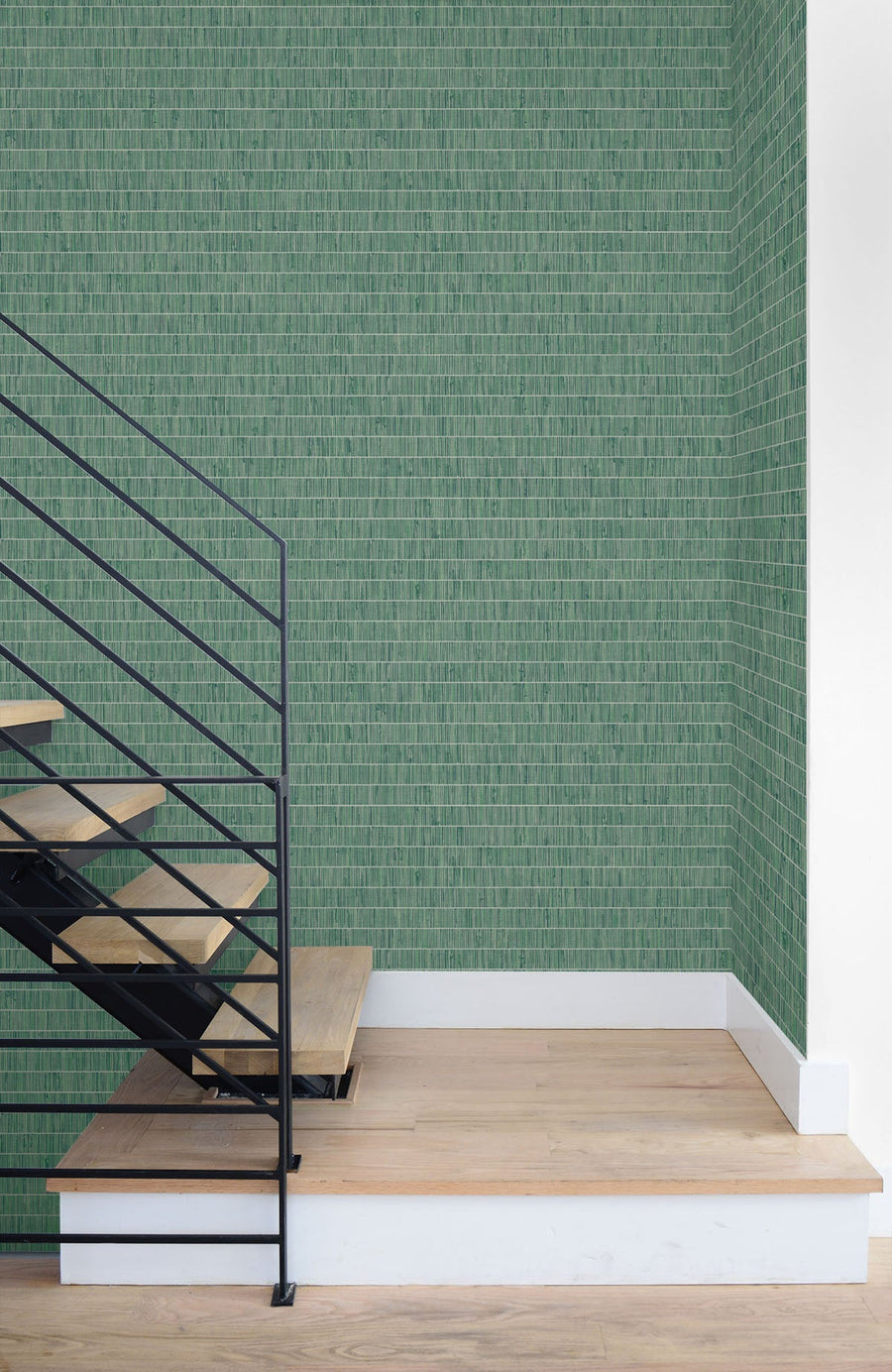 Modern staircase with wooden steps and metal railings against a green patterned wall.