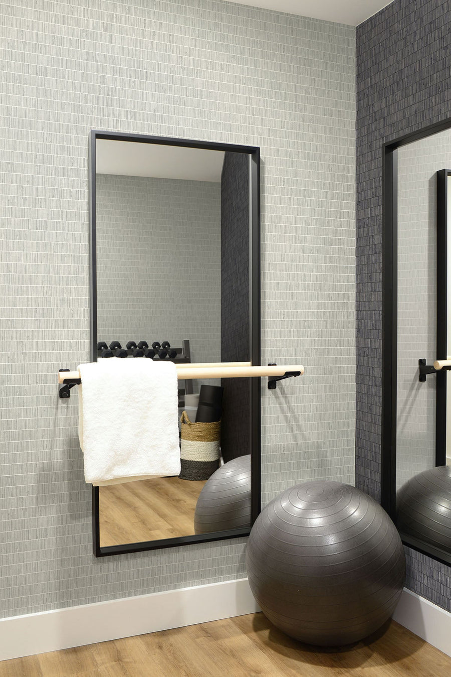 Bathroom with a large mirror, towel, and exercise ball against a tiled wall.