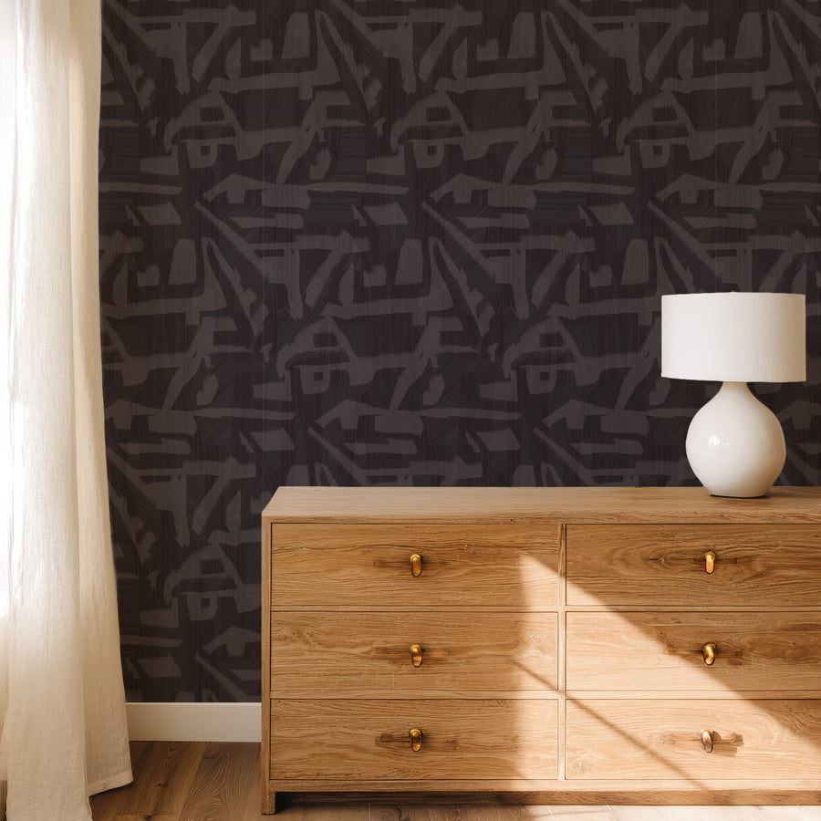 Bedroom with wood dresser and table lamp featuring Abstract Brushstroke Wallpaper Charcoal Grey accent wall