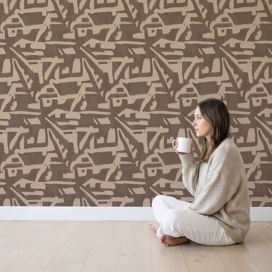 Living area with woman seated cross-legged holding a mug featuring Abstract Brushstroke Wallpaper Taupe Brown accent wall