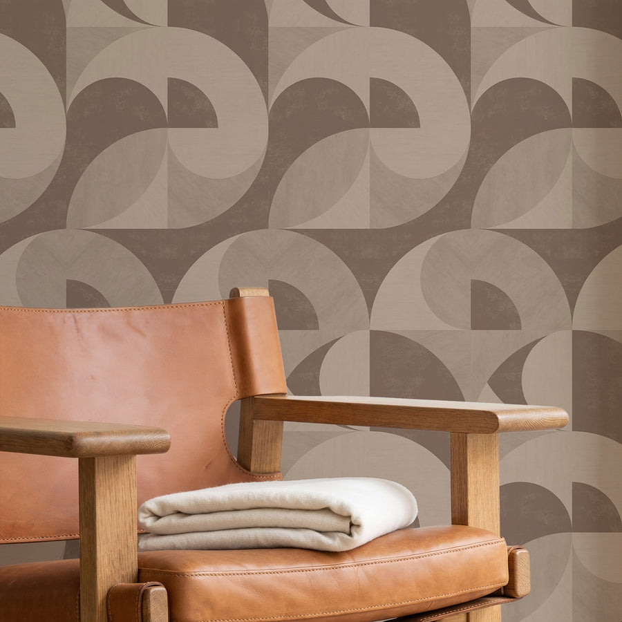 Brown leather armchair with folded blankets featuring Bauhaus Geometric Shapes Wallpaper Brown Tan by Petra Kohlmayr
