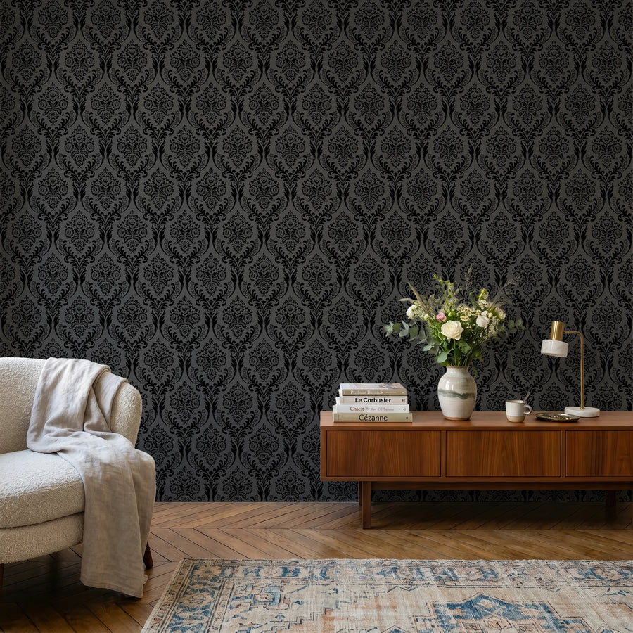 Black damask wallpaper in a sitting room with a cream chair