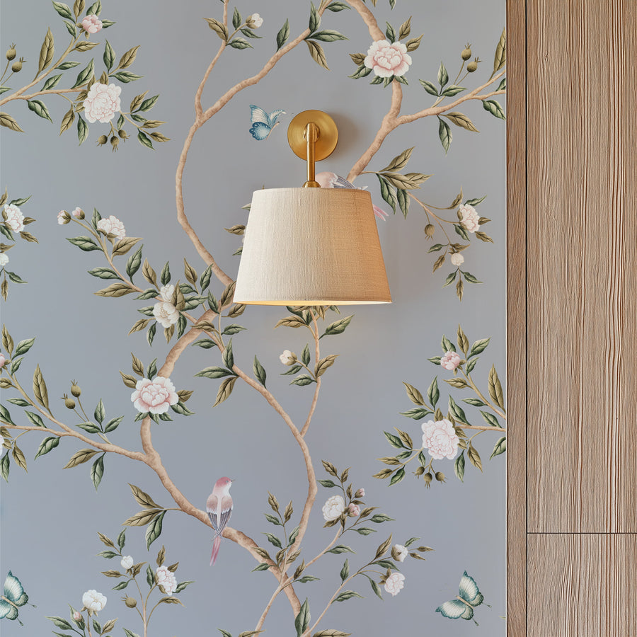 Blue wall with brass wall sconce and climbing floral branches featuring Blue Chinoiserie Hemma Wallpaper Floral Garden Birds by Maja Pitschmann