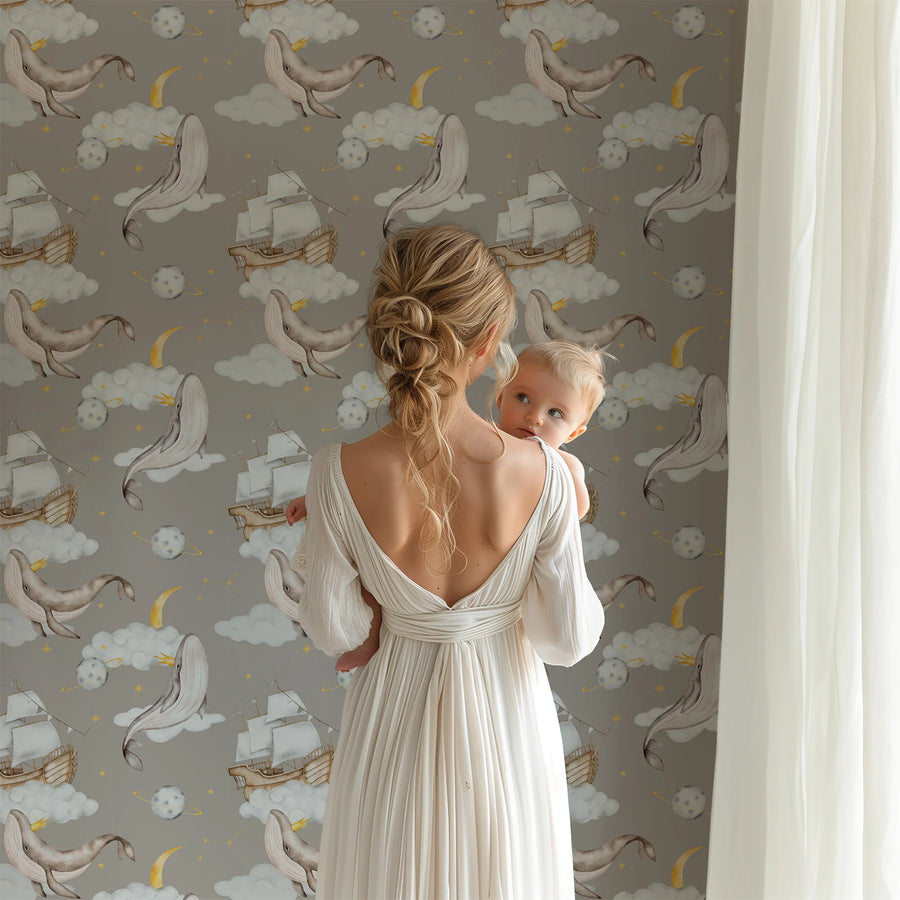 Taupe celestial whale nursery wallpaper behind a parent holding a baby by the window