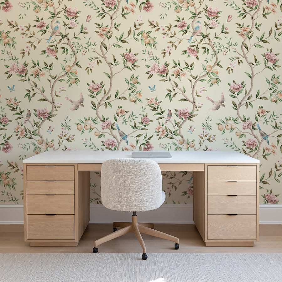 Home office with wood desk white chair and potted plant featuring Chinoiserie Floral Garden Bird Wallpaper Blush Cream accent wall