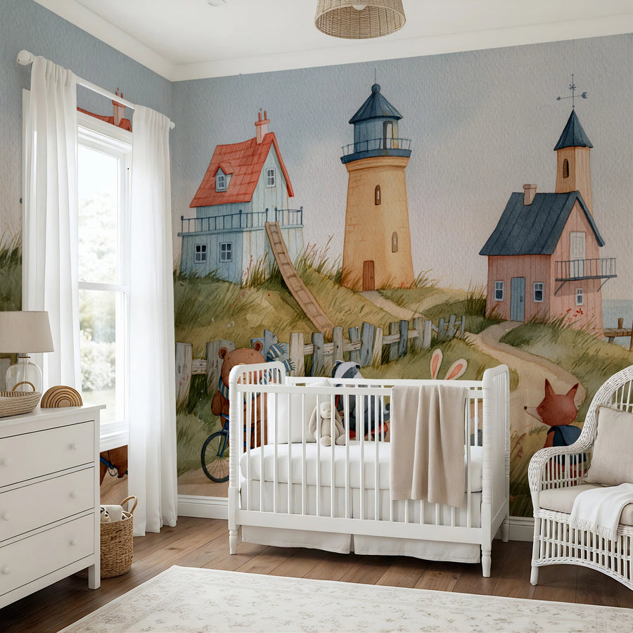 Lighthouse nursery wall mural with seaside cottages behind a white crib and wicker chair