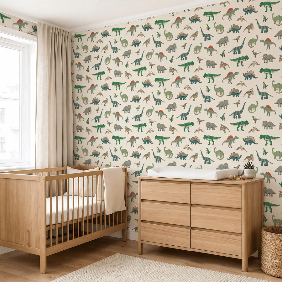 Cartoon dinosaur wallpaper on cream in a nursery with a wooden crib and dresser