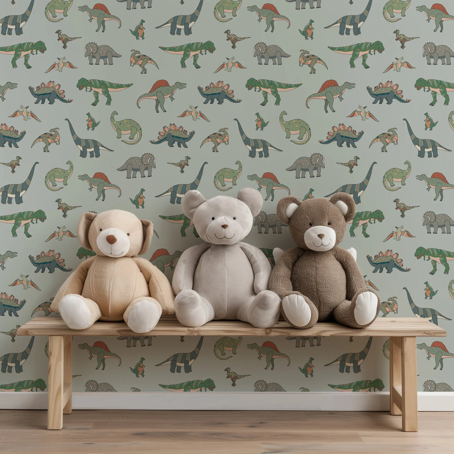 Sage green dinosaur kids wallpaper behind three teddy bears on a wooden bench