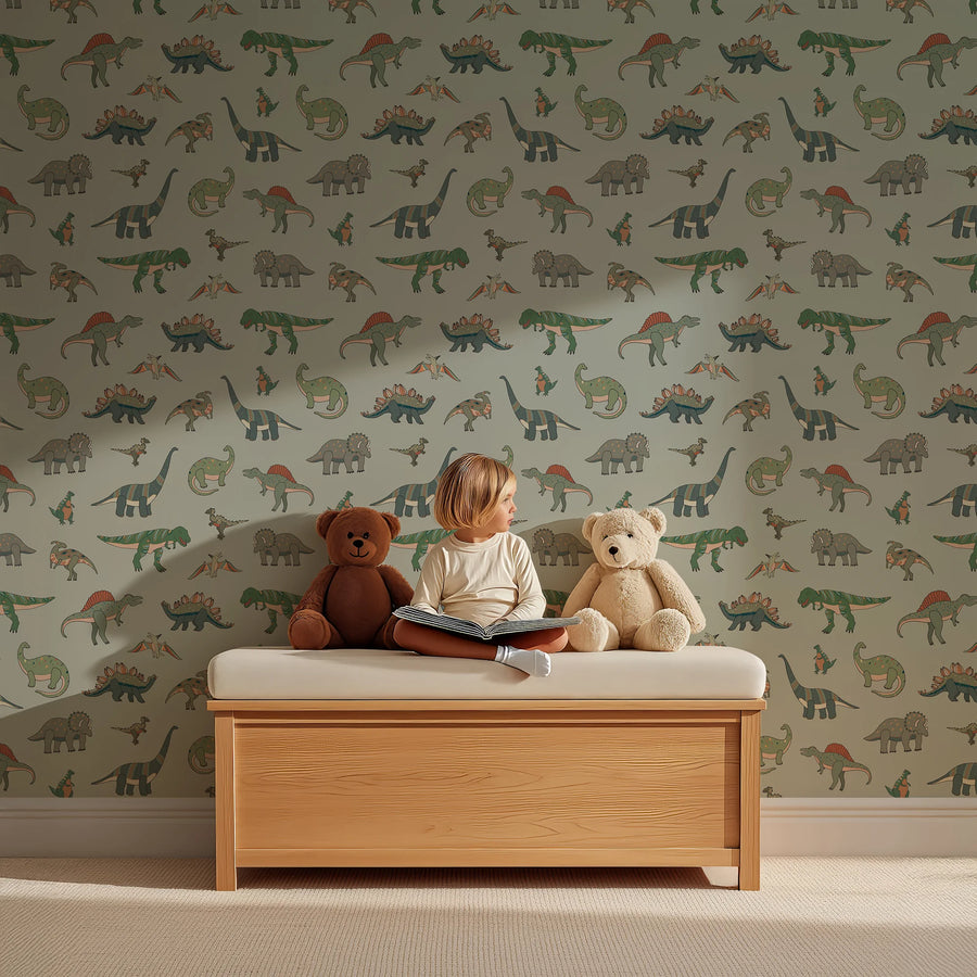 Cartoon dinosaur wallpaper in sage green behind a child reading on a wooden bench with teddy bears