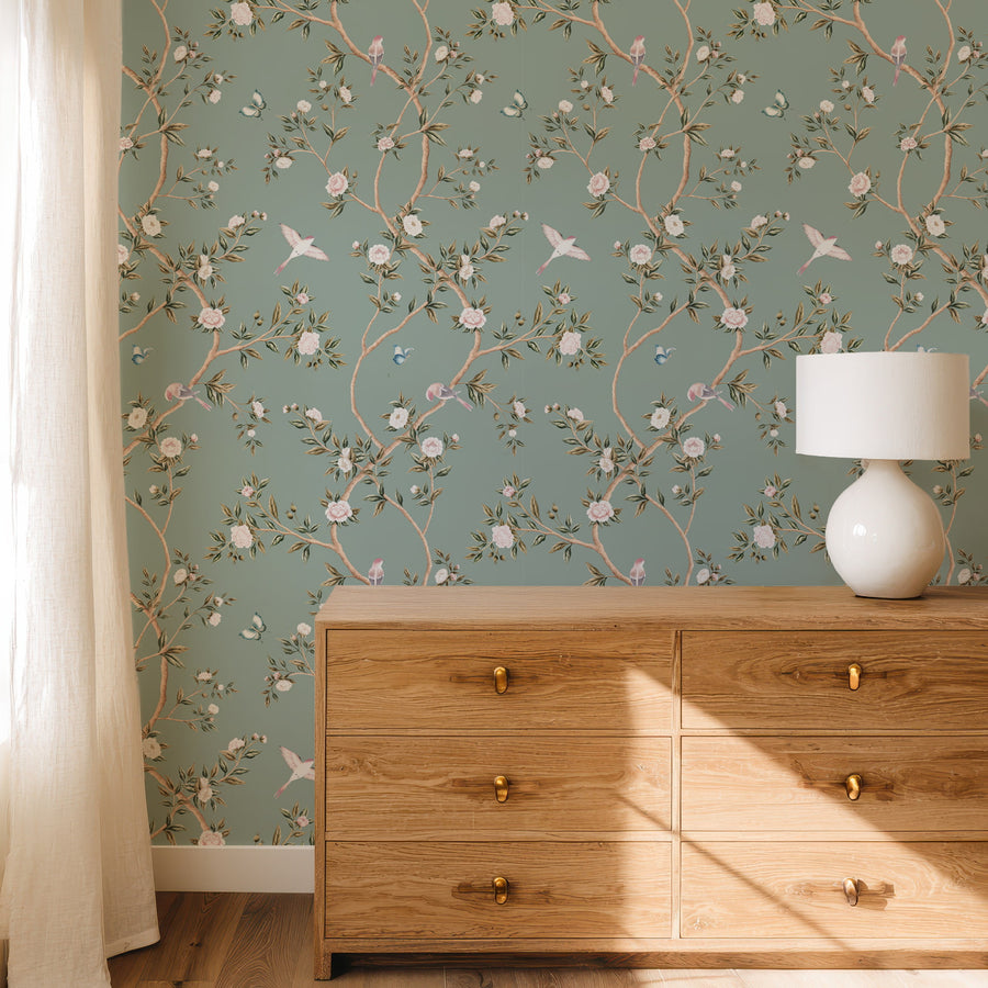 Bedroom with wood dresser and table lamp featuring Light Green Chinoiserie Hemma Wallpaper Floral Garden Birds accent wall