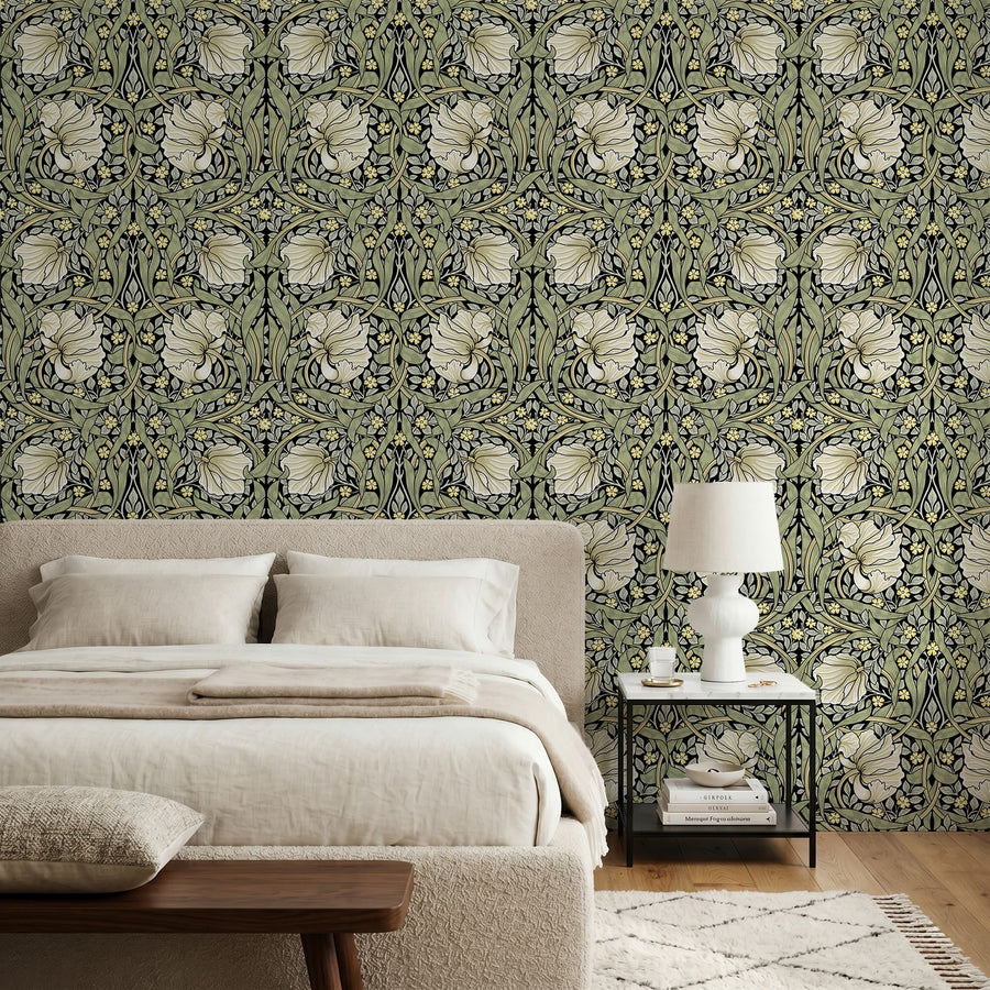 Olive green and cream William Morris Pimpernel wallpaper in a bedroom behind a linen bed