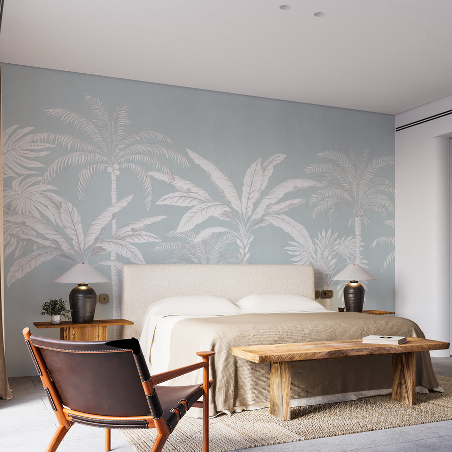 Pastel blue palm tree wallpaper mural in a bedroom behind a linen bed