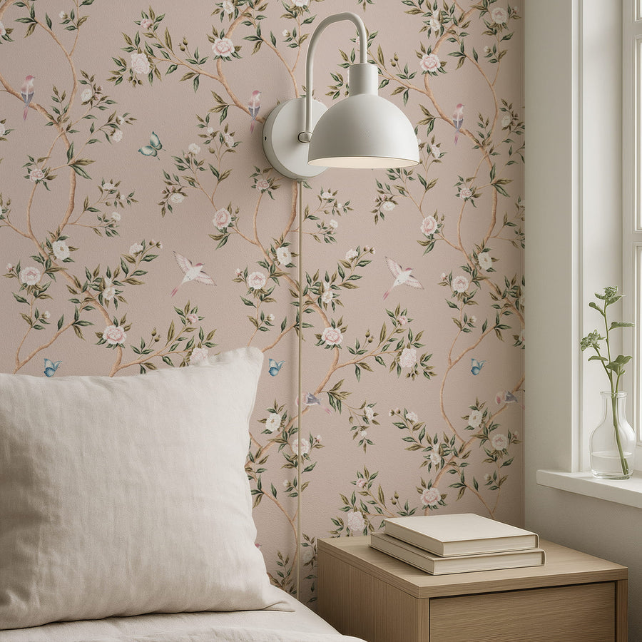 Bedroom with cream pillow stacked books and wall sconce featuring Pink Chinoiserie Hemma Wallpaper Floral Garden Birds accent wall