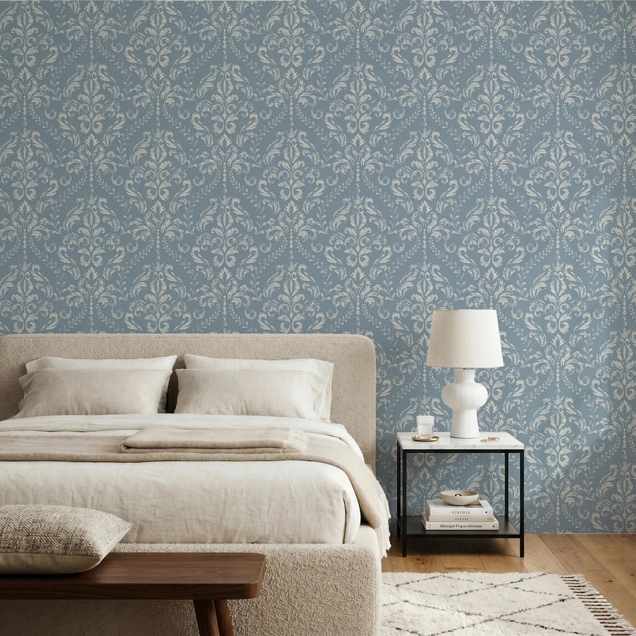 Vintage blue damask wallpaper in a bedroom with linen bedding