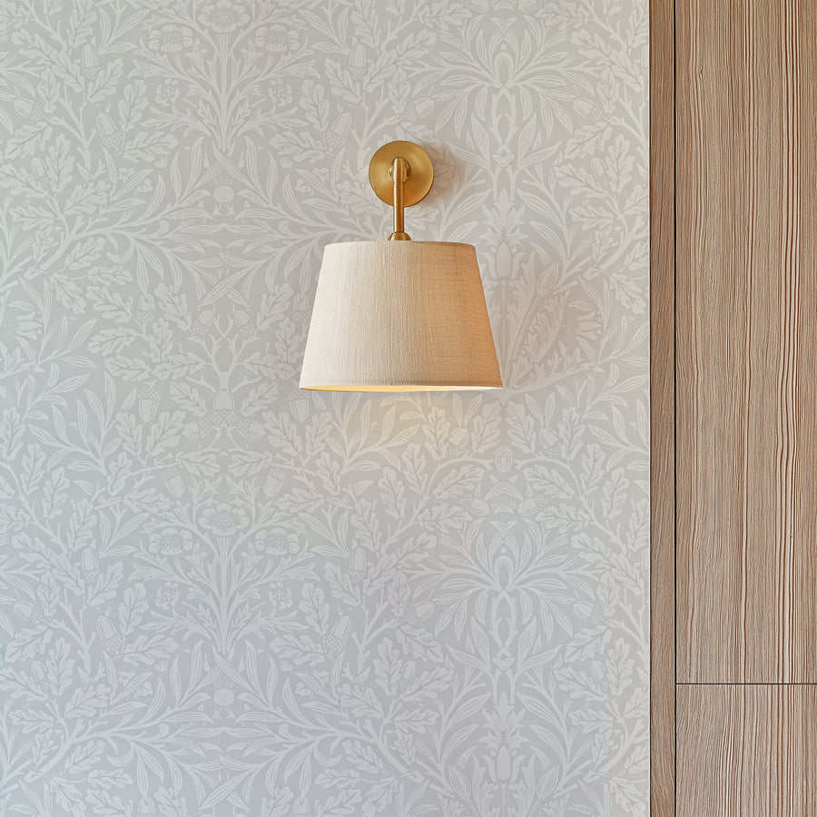 William Morris Acorn grey wallpaper detail behind a brass wall sconce