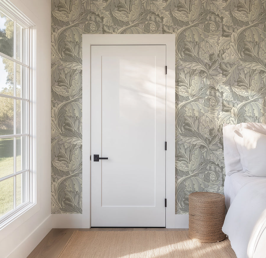 Gray Acanthus William Morris wallpaper behind a wicker armchair in a sitting room