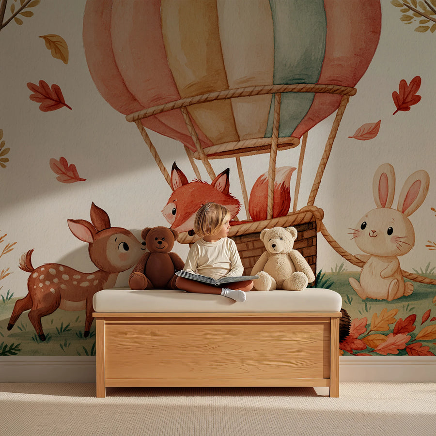 Woodland animals nursery wall mural with a hot air balloon, fox, fawn and bunny behind a child reading on a wooden toy bench
