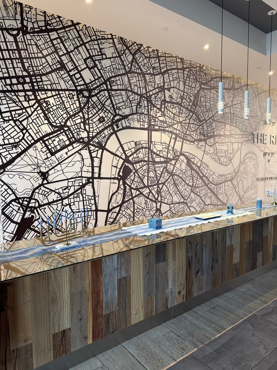 Modern interior with a large wall mural of a city map and a wooden reception desk.