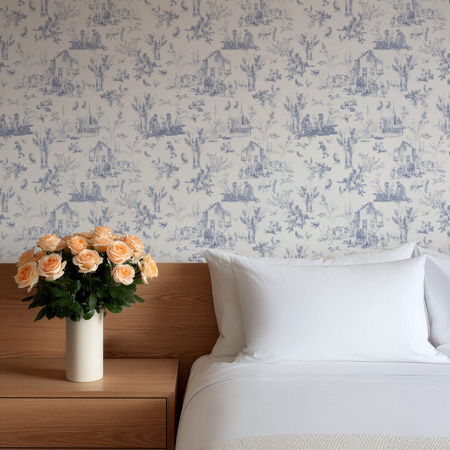 Bedroom with floral arrangement on a nightstand against a Blue Village Toile Wallpaper – French Country Life Pattern