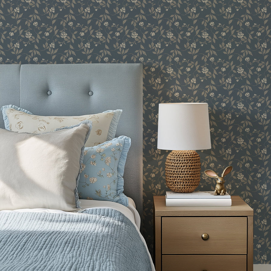 Bedroom with navy blue floral wallpaper, gray upholstered headboard, and wooden nightstand with lamp and decor.