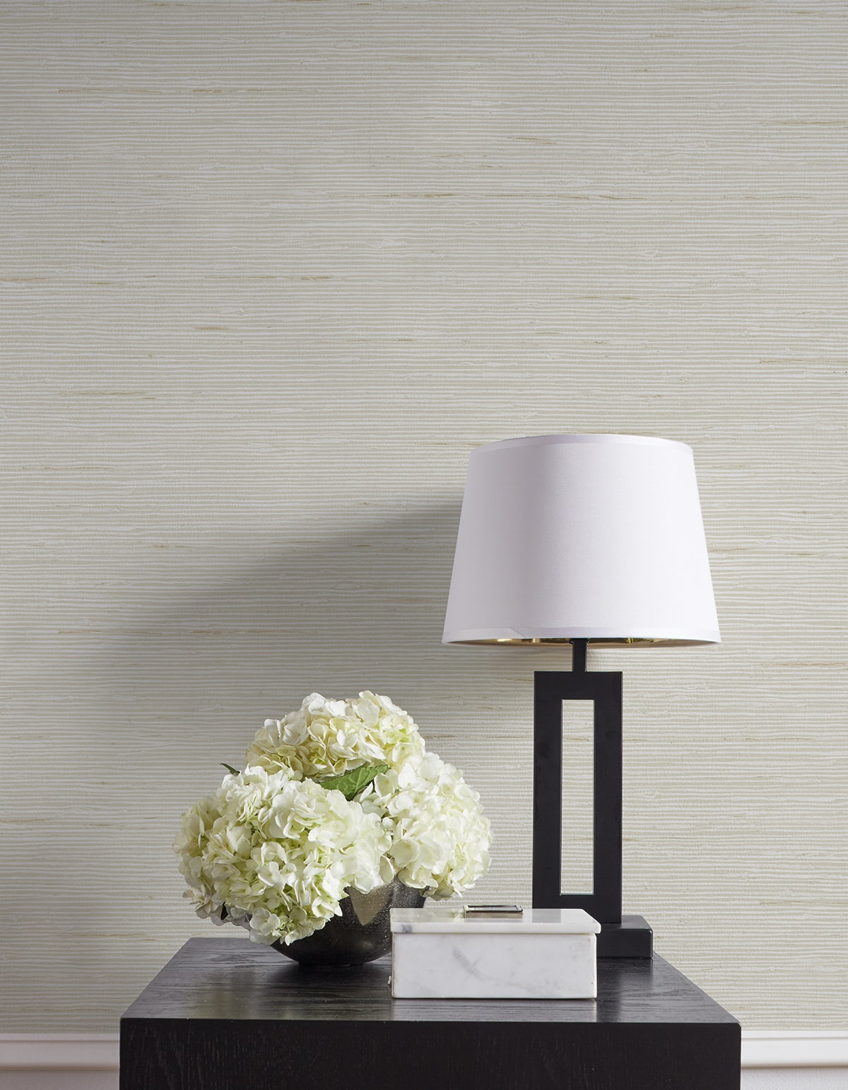 Modern lamp and floral arrangement on a table against a textured wall.