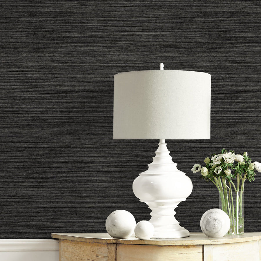 White table lamp on a wooden surface with dark textured wallpaper in the background