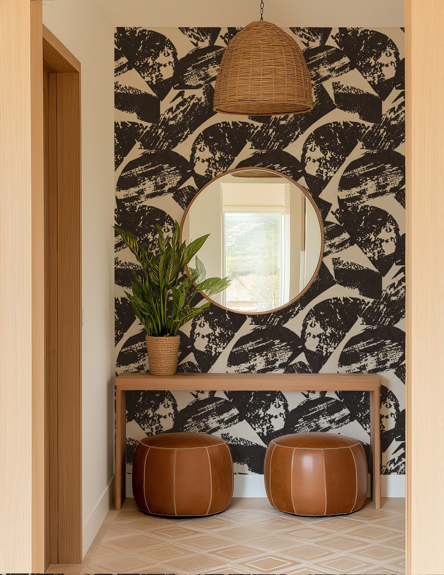 Foyer with Black and White Abstract Woodcut Wallpaper, round mirror, and brown ottomans.
