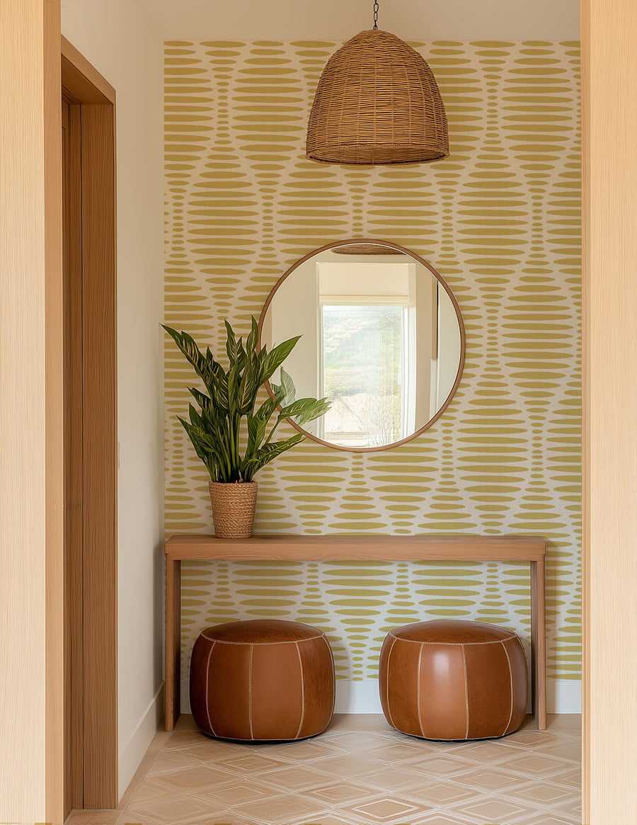 Foyer with round mirror, plant, and leather stools against a Ogee Sketch Ovals Wallpaper - Mustard Yellow