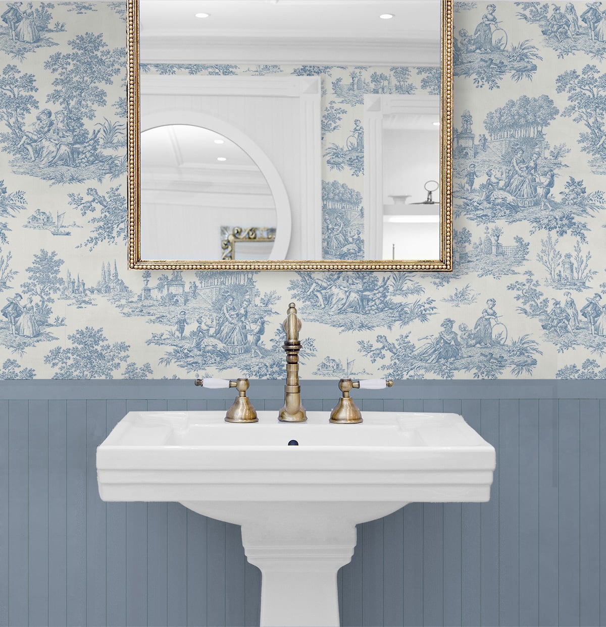 Bathroom with white pedestal sink, gold fixtures, and blue toile wallpaper.