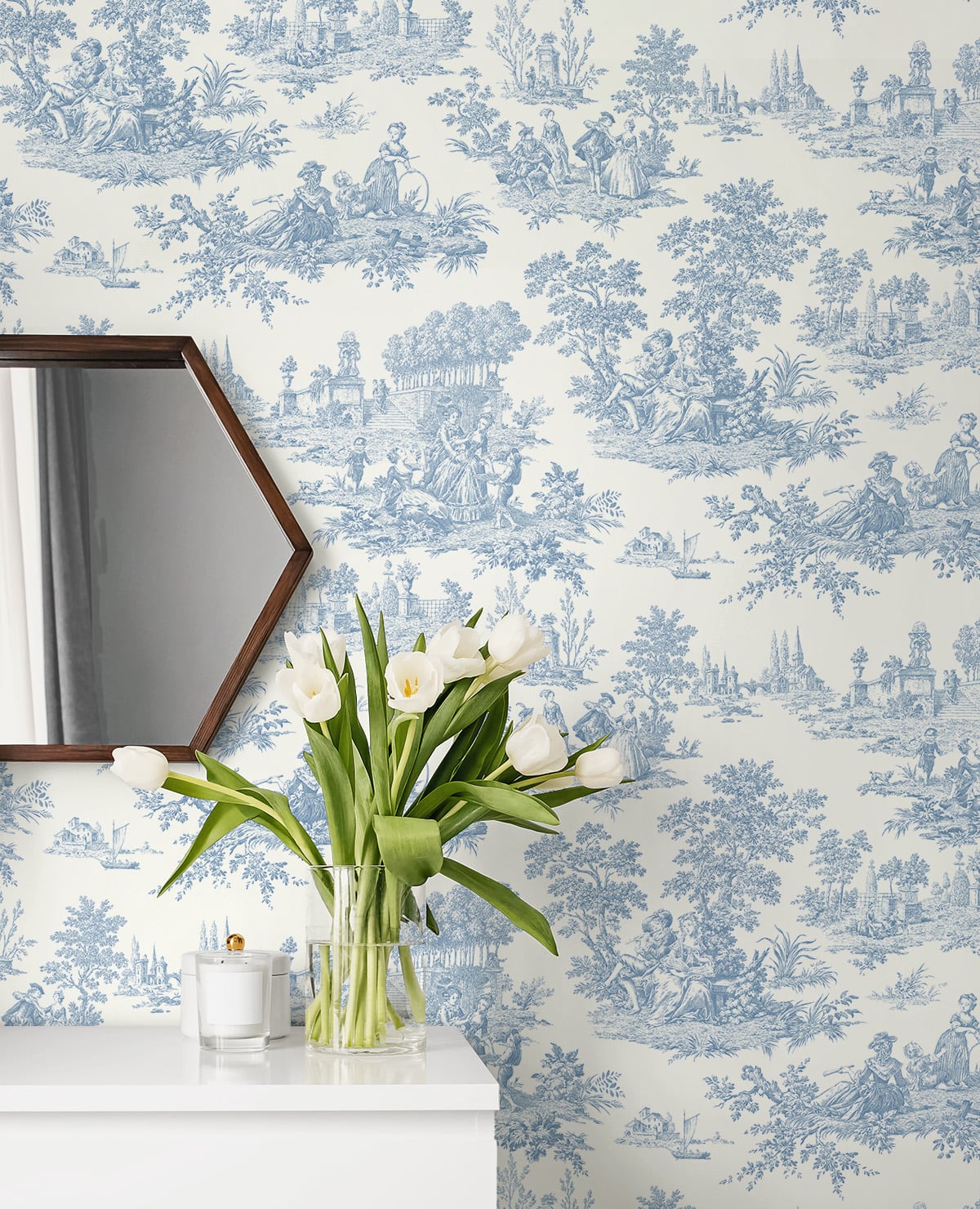 Wallpaper with blue floral pattern, mirror, and vase of white tulips on a shelf.