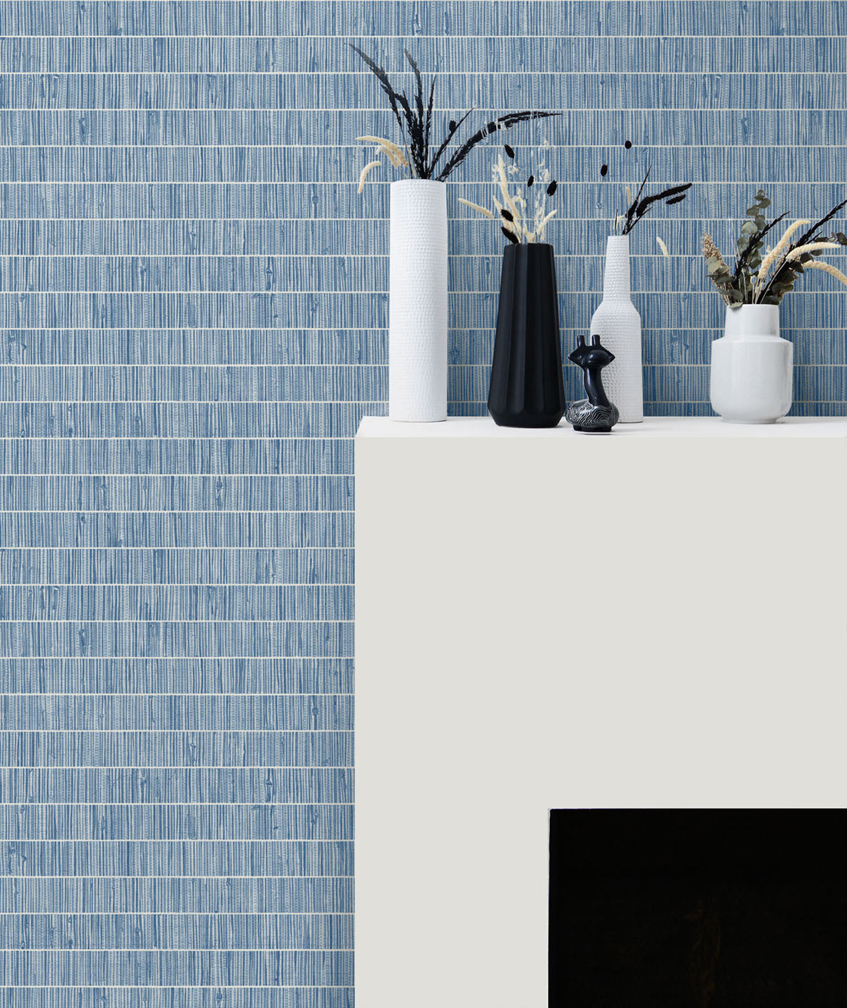 Decorative arrangement of vases and plants on a white surface with a blue tiled wall background