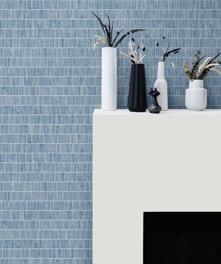 Decorative arrangement of vases and plants on a white surface with a blue tiled wall background