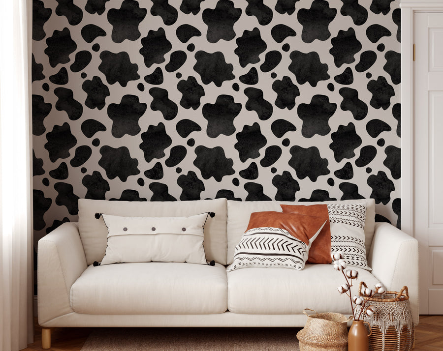 White sofa with patterned cushions against a black and white cow print wallpaper