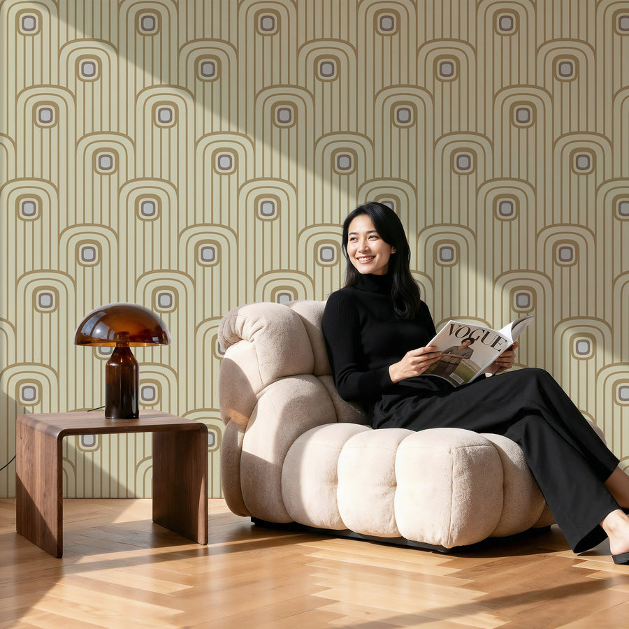 Woman reading a magazine on a beige armchair against a Warm Beige 70s Retro Mod Arch Geometric Wallpaper