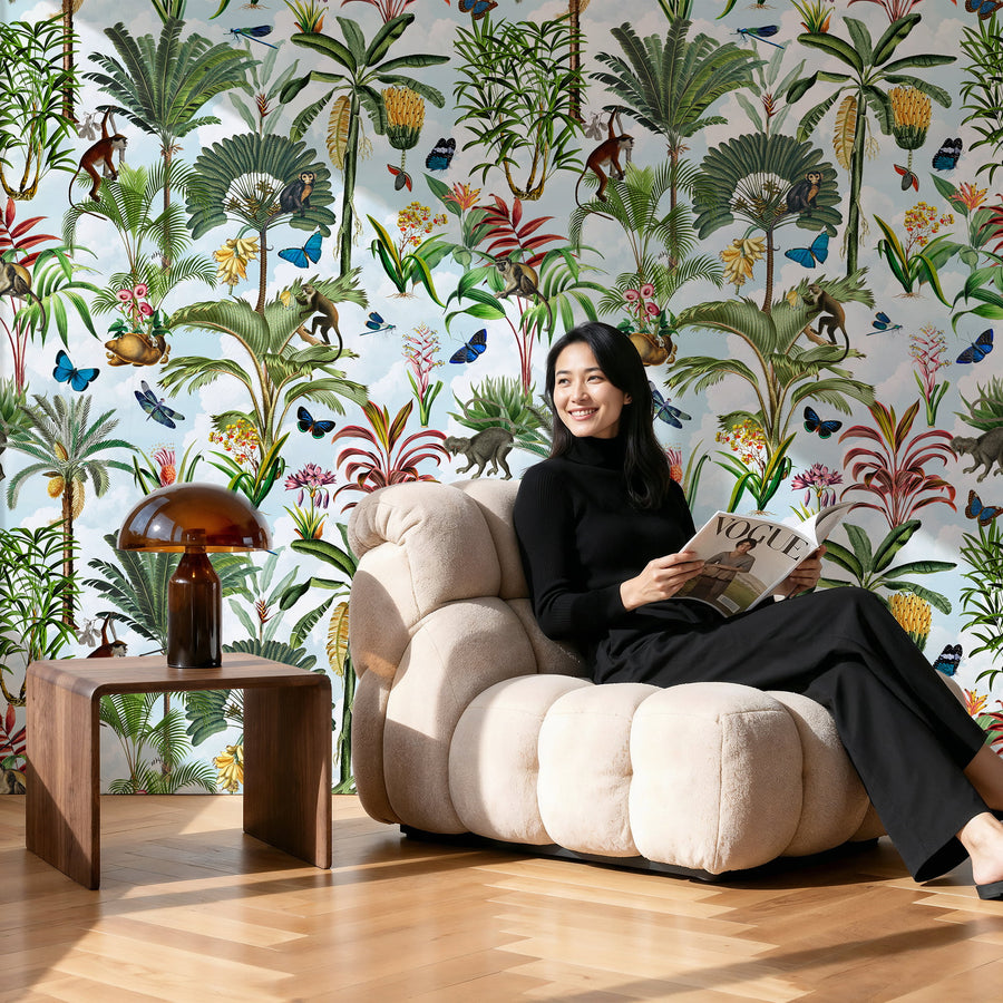 Woman sitting on a beige armchair reading a magazine against a Tropical Blue Sky Wallpaper – Jungle with Monkeys & Palms