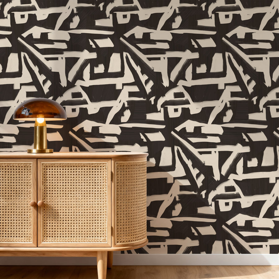 Wooden cabinet with wicker doors against a black and white abstract patterned wallpaper