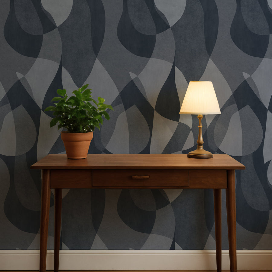 Wooden desk with a lamp and plant against a Mid-Century Abstract Curves Wallpaper – Navy & Slate Blue