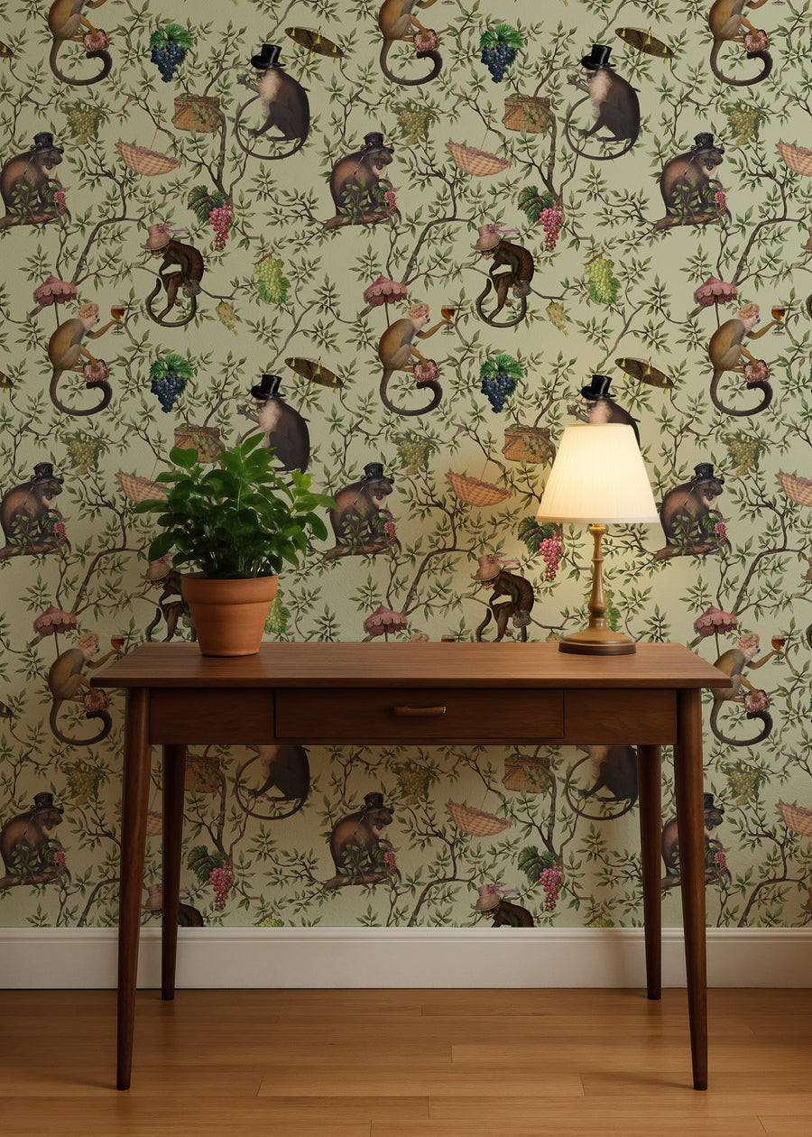 Wooden desk with a lamp and plant against a wallpapered wall with monkey designs.