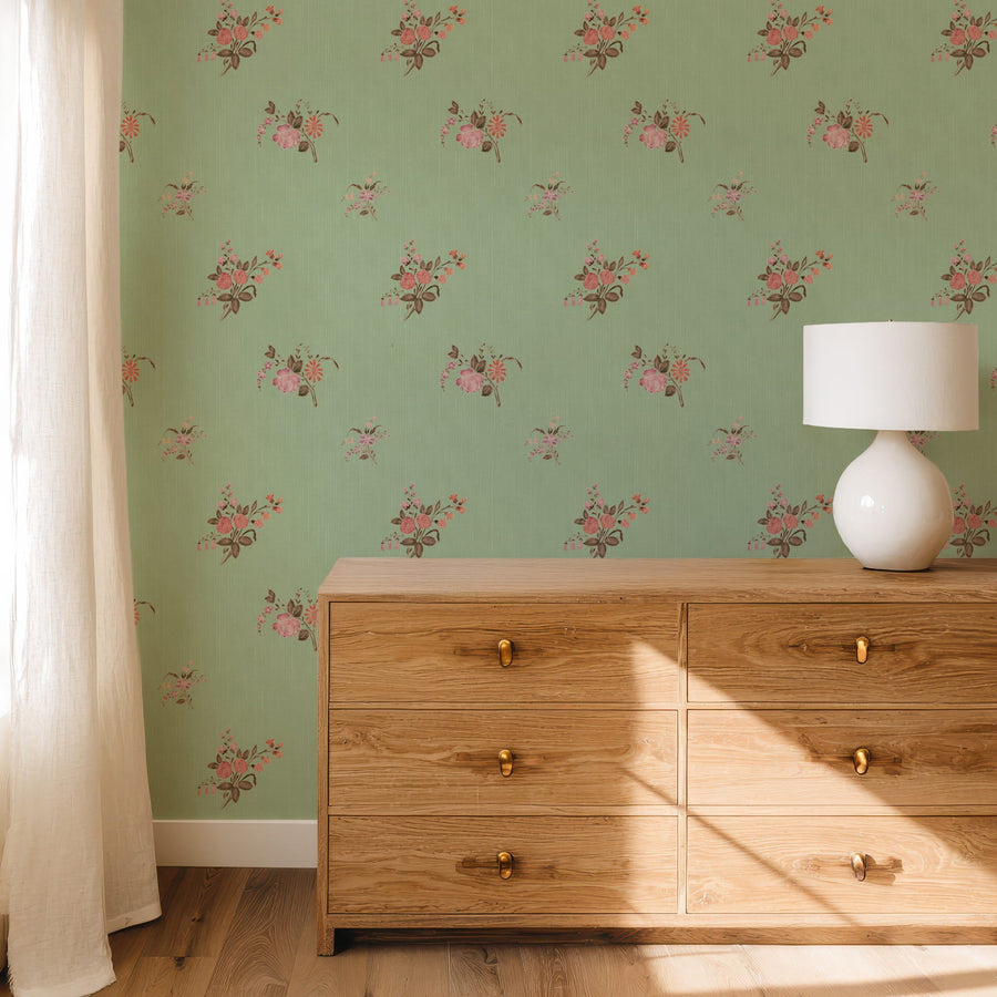 Wooden dresser against a Sage Heritage Heirloom Floral Wallpaper with a lamp on top.
